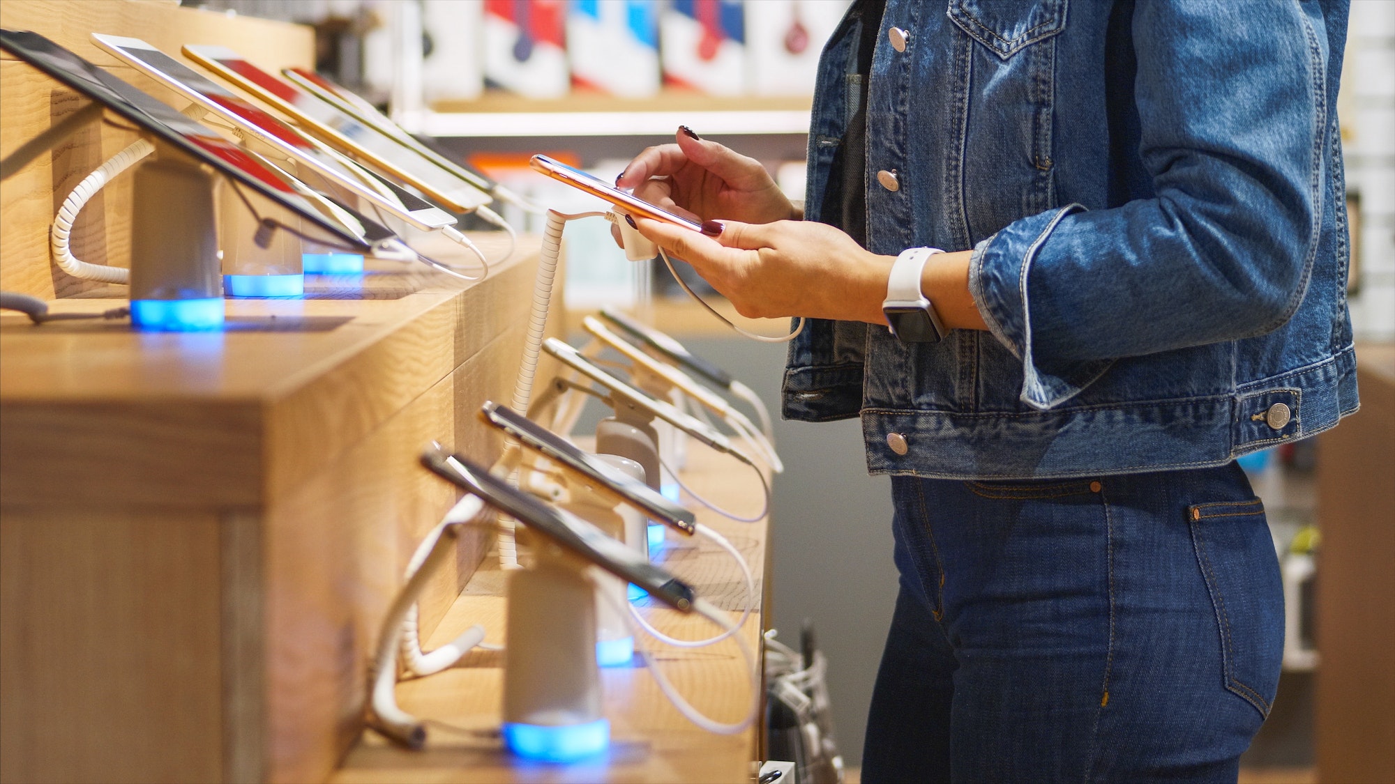 Young woman chooses a smartphone in an electronics store