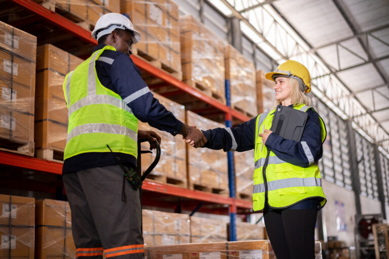 Industry warehouse worker in helmets with produce order details and checking goods supplies on boxes